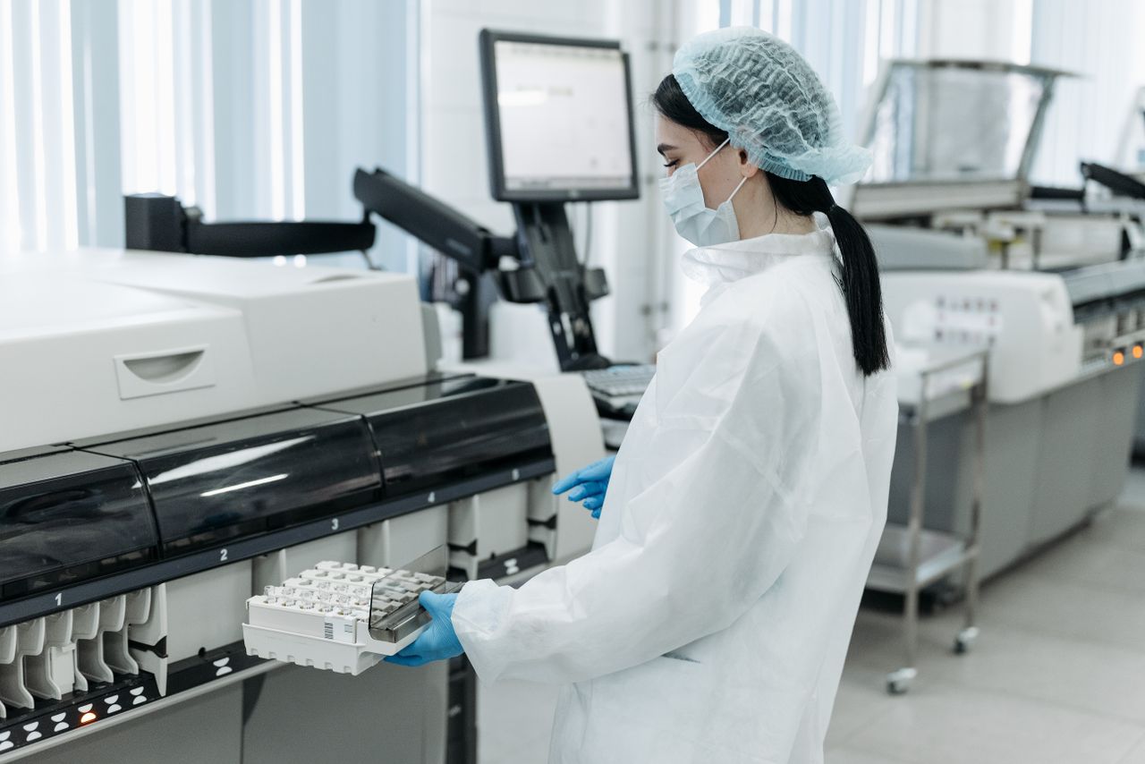 Laboratory worker in protective gear handling diagnostics equipment.